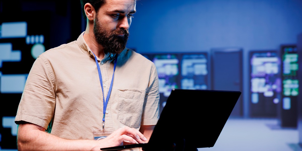 A male technitian holding a laptop in a server room